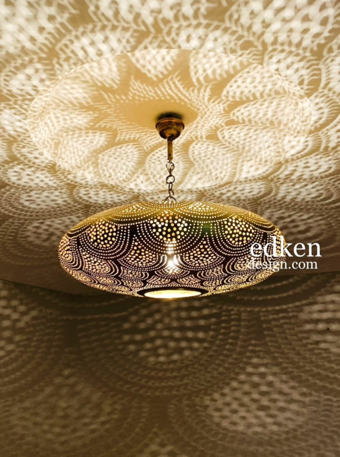 Close-up of a handmade Moroccan pendant light in gold brass with intricate perforated patterns.