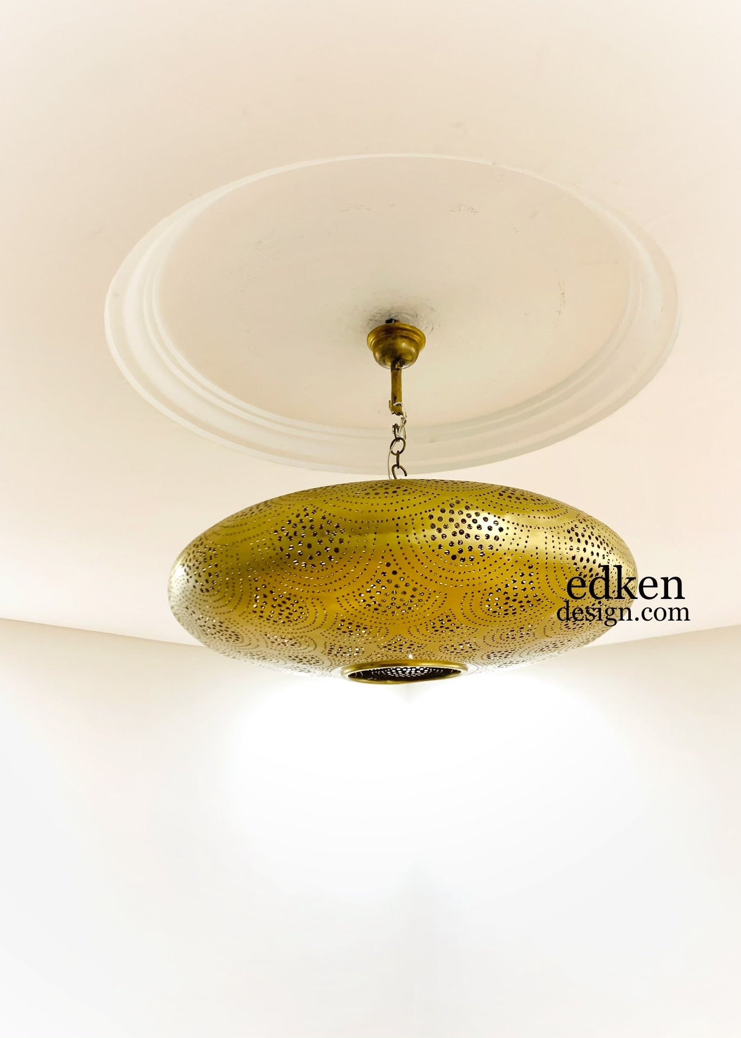 Intricate floral shadow patterns on a ceiling created by a handcrafted Moroccan brass lamp.
